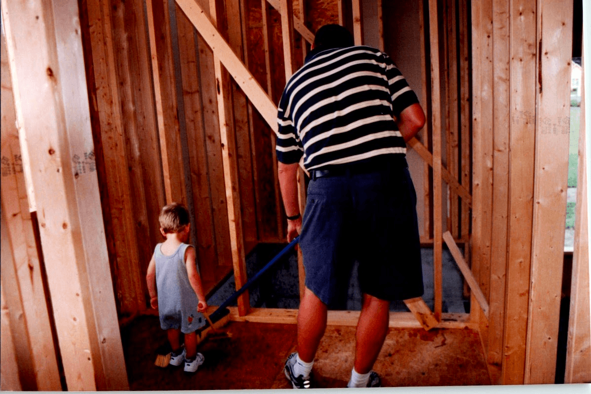 Dad working inside a framed house while I follow along with a toy paint roller