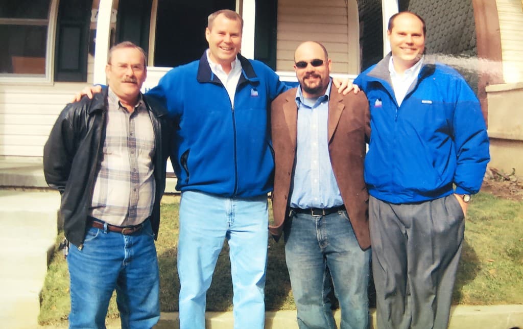 Jim Halbert and three others on site in front of a Habitat for Humanity home, two in Classic Communities fleeces
